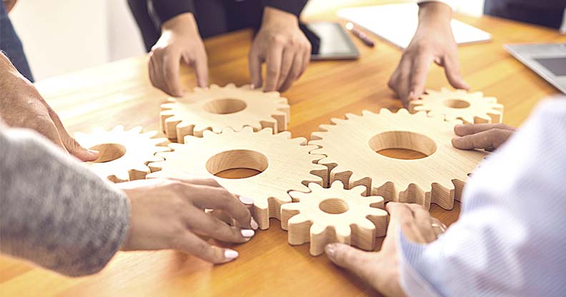 Mains qui assemblent des engrenages en bois