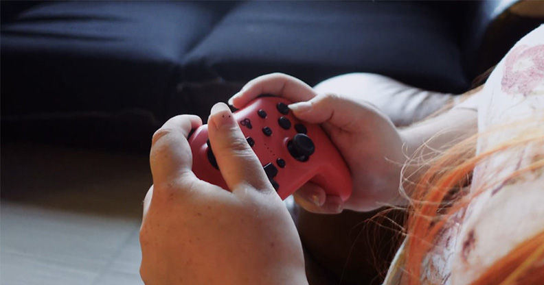 Mains qui tiennent une manette de console vidéo