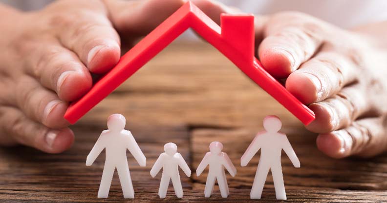Mains tenant une maison en plastique et des figurines